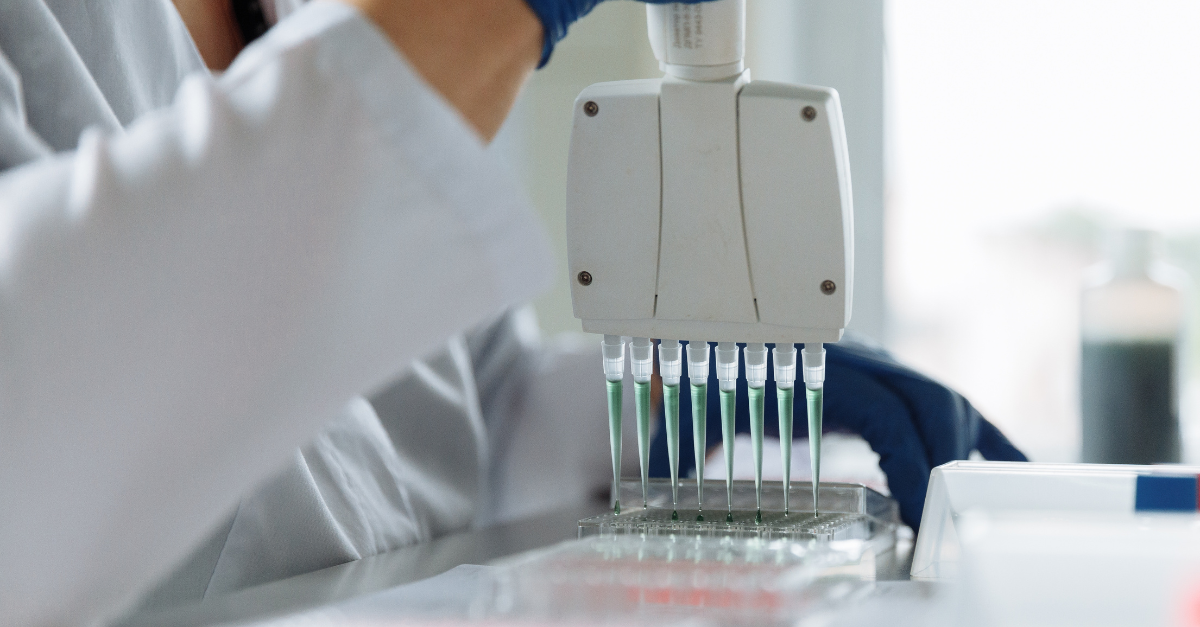 A scientist observing multiple vials of liquid under a microscope