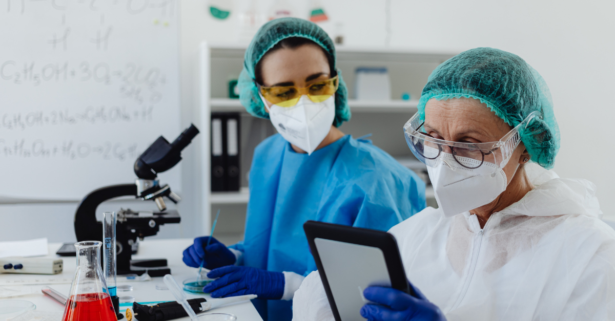 Two scientists in a laboratory comparing notes on a tablet