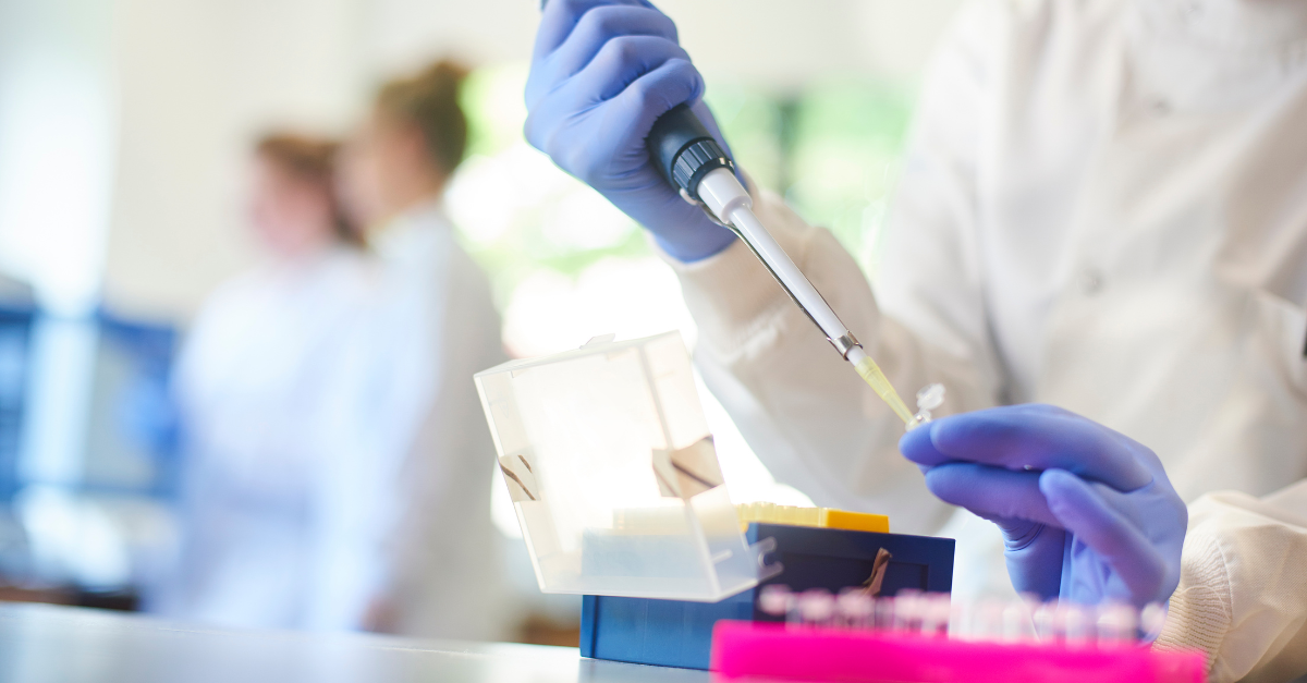 A scientist squeezing liquid out of a device into test tubes